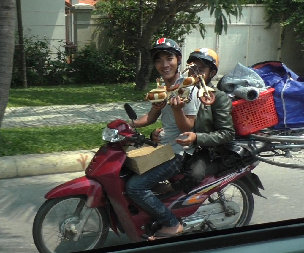 Selling wooden motorcycle while driving another motorcycle